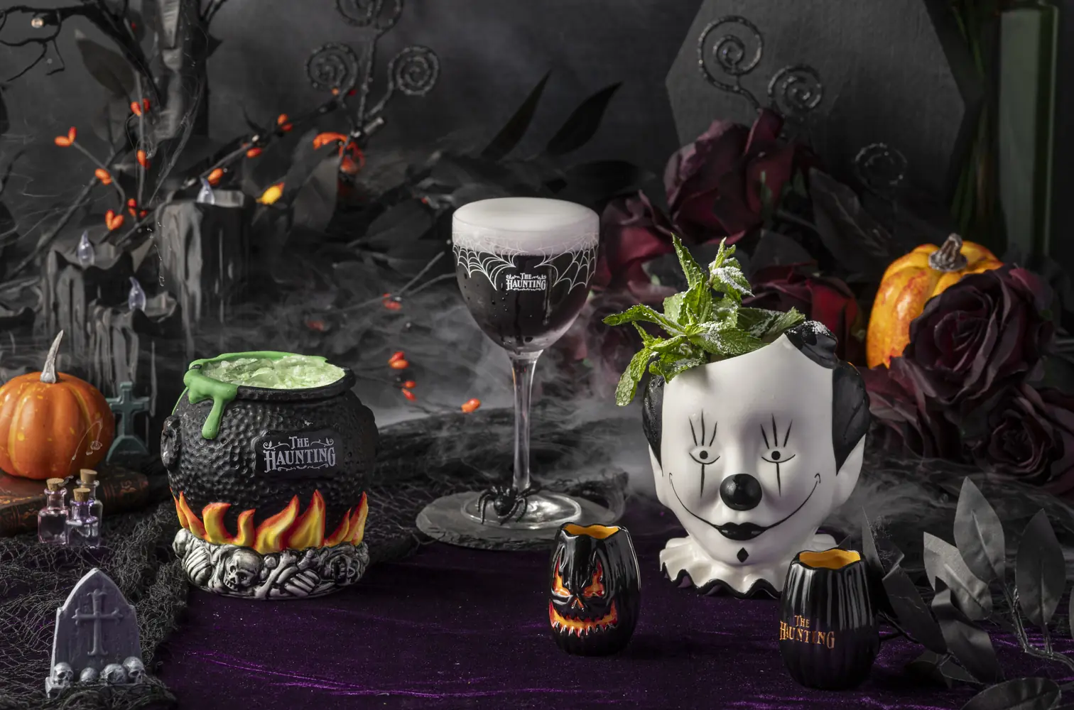 A spread of Haunting cocktails among candles, pumpkins and fog